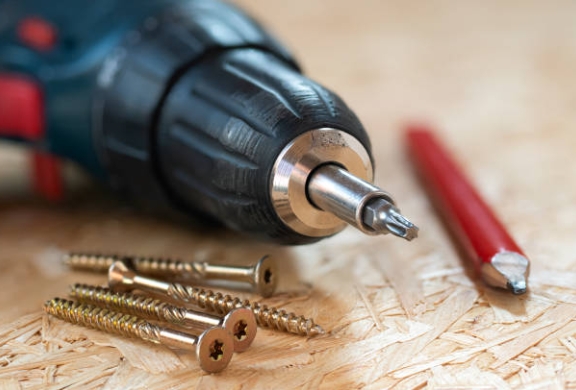 Drill with screws and pencil nearby